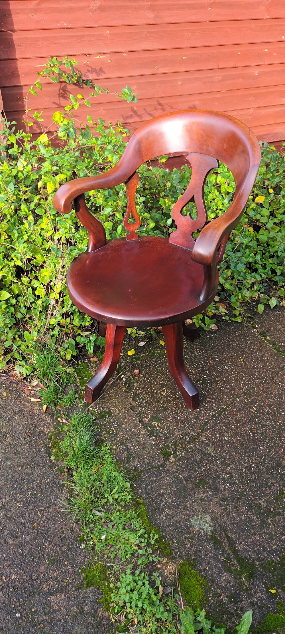 A late Victorian reddish-brown mahogany revolving desk armchair featuring a curved backrest with a pierced splat and a solid wooden seat resting on a swivel base. View IV