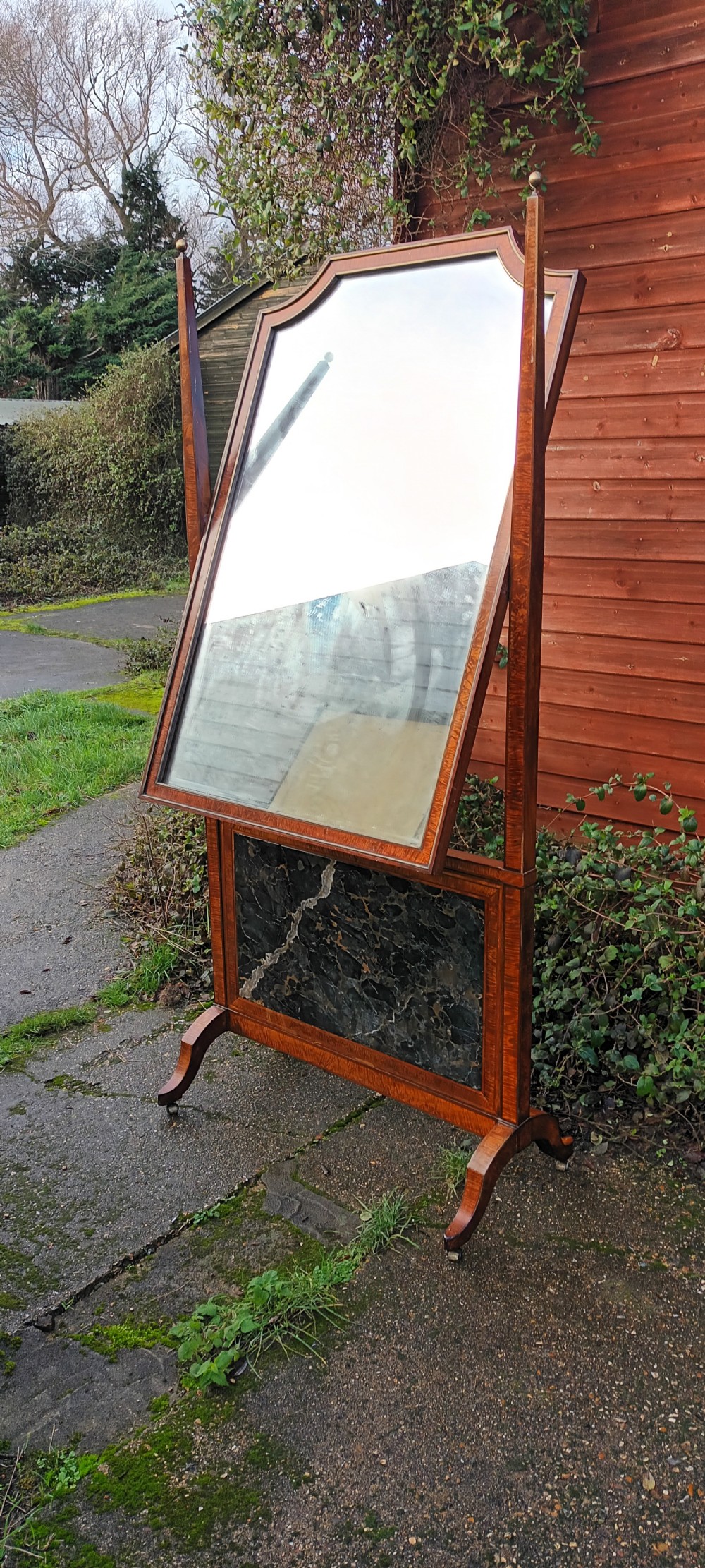 An early nineteenth-century timber cheval mirror featuring a shaped crest, slender side posts with finials, and a fold-down lower marble panel resting on splayed feet. View X