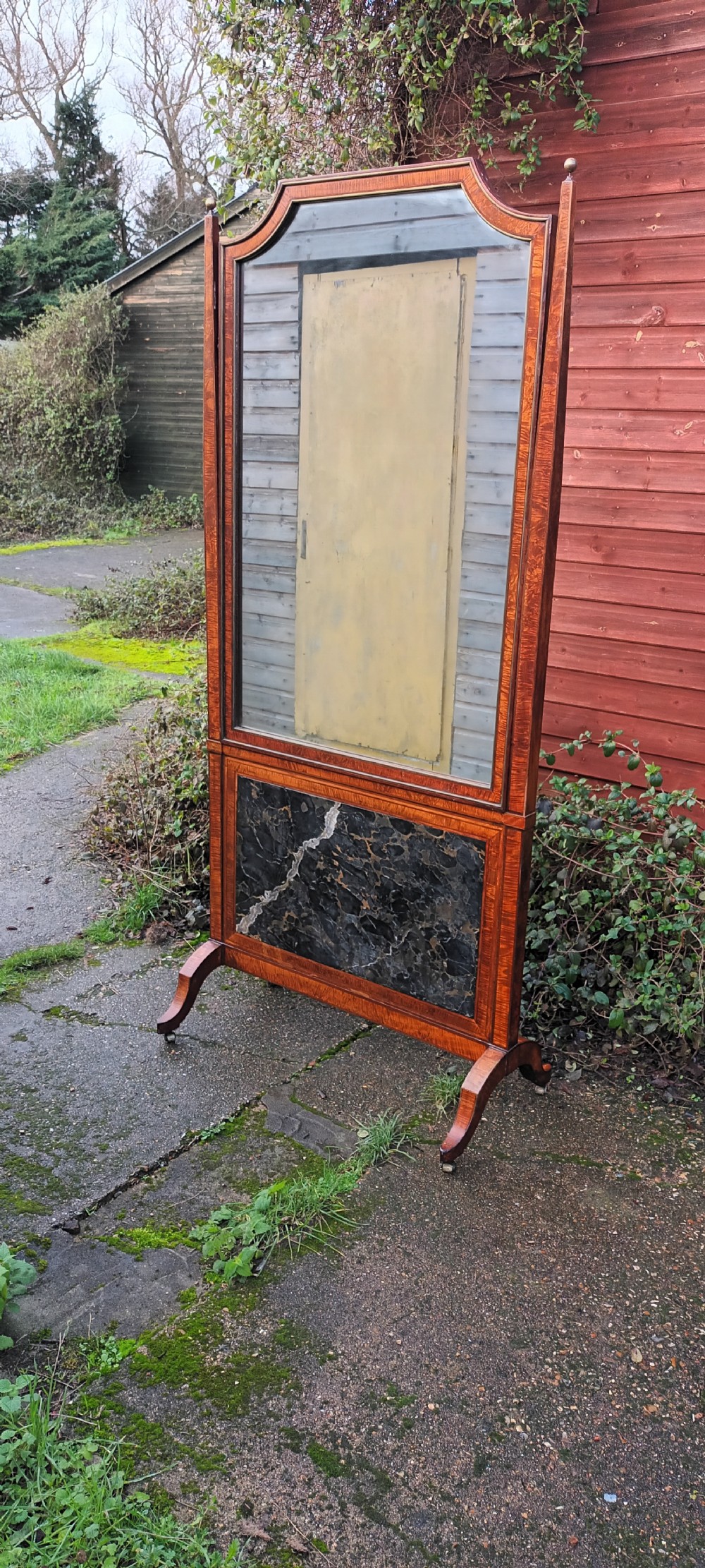 An early nineteenth-century timber cheval mirror featuring a shaped crest, slender side posts with finials, and a fold-down lower marble panel resting on splayed feet. View XI