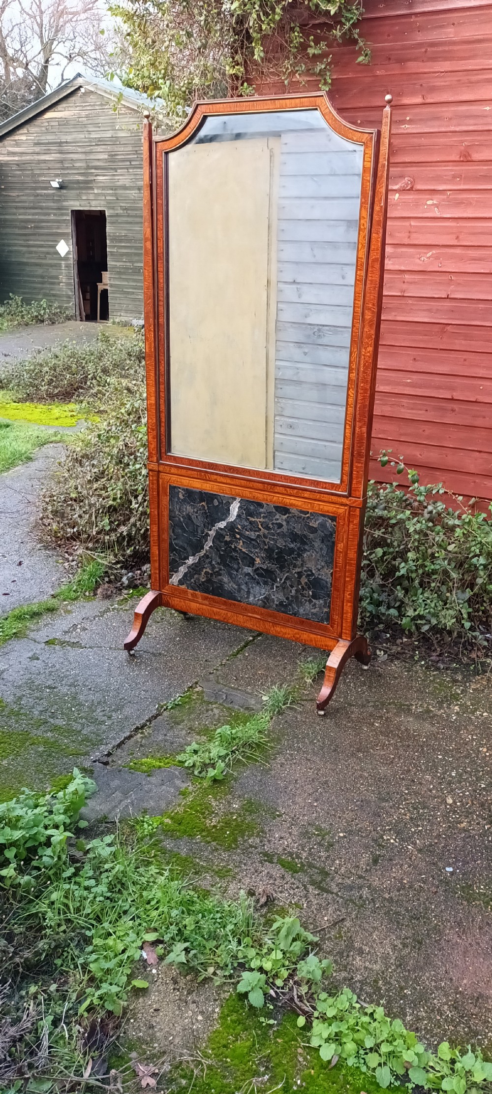 An early nineteenth-century timber cheval mirror featuring a shaped crest, slender side posts with finials, and a fold-down lower marble panel resting on splayed feet. View XIV
