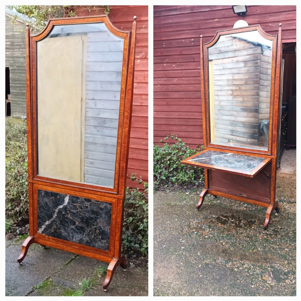 An early nineteenth-century timber cheval mirror featuring a shaped crest, slender side posts with finials, and a fold-down lower marble panel resting on splayed feet.