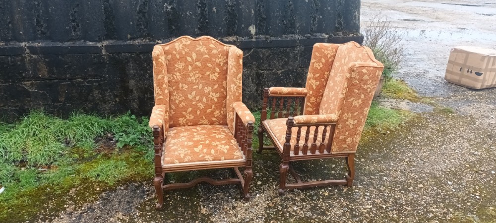 A pair of Edwardian high-back armchairs featuring carved oak frames, turned spindle arm supports, and patterned terracotta floral fabric upholstery. View VII
