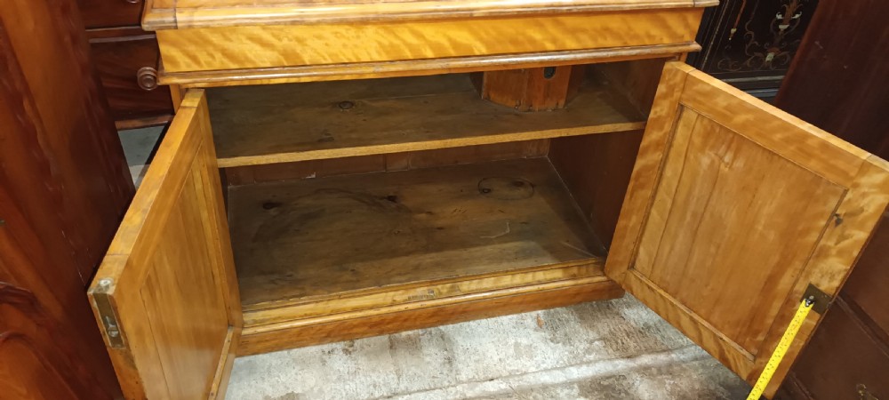 A Victorian satin birch washstand cabinet with a hinged lid raised to show circular cutouts above two panelled doors. View VI