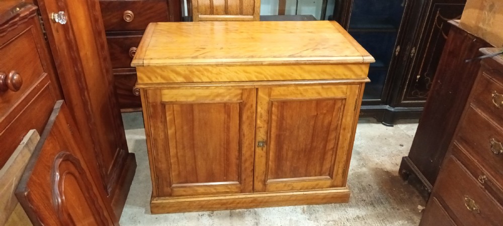 A Victorian satin birch washstand cabinet with a hinged lid raised to show circular cutouts above two panelled doors. View IX