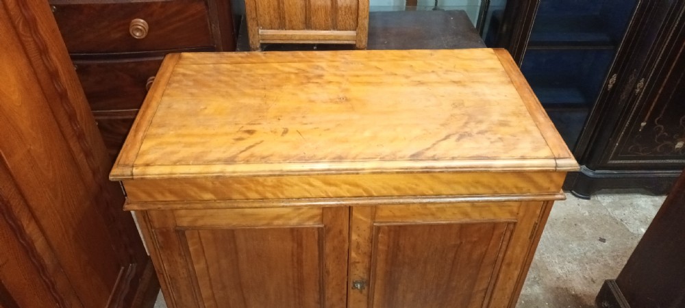 A Victorian satin birch washstand cabinet with a hinged lid raised to show circular cutouts above two panelled doors. View X