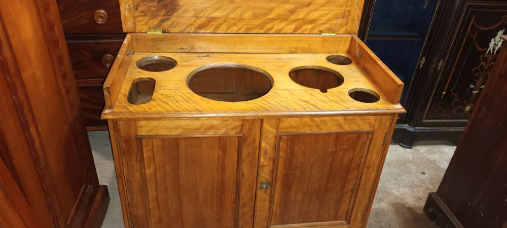 A Victorian satin birch washstand cabinet with a hinged lid raised to show circular cutouts above two panelled doors. View XV