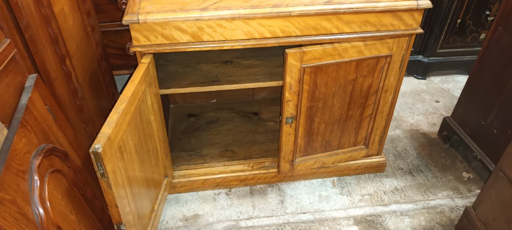 A Victorian satin birch washstand cabinet with a hinged lid raised to show circular cutouts above two panelled doors. View XVI