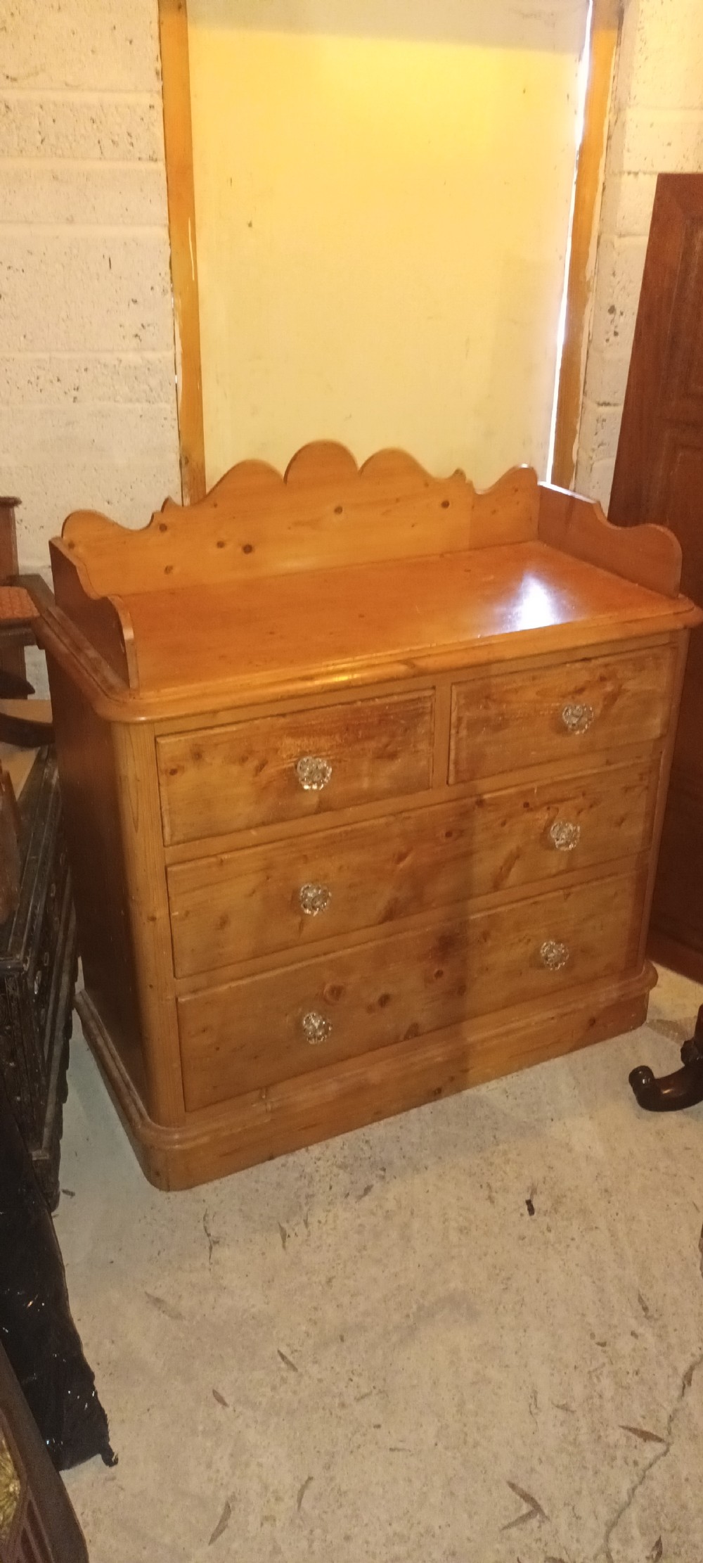 A Victorian pine chest of drawers featuring a scalloped gallery top, two short drawers over two long drawers, and clear glass knobs. View VII