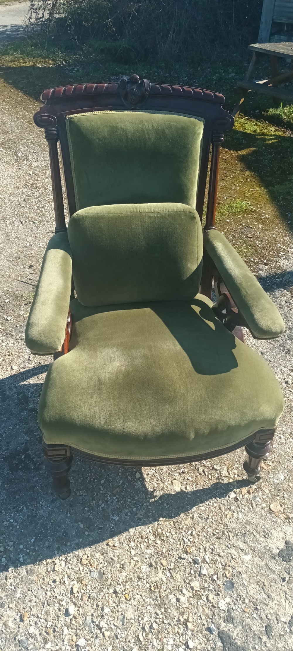A late Victorian mahogany armchair upholstered in olive green velvet with carved openwork arm supports and turned front legs on castors. View VI