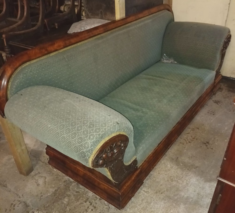 A 19th-century mahogany hall sofa featuring carved floral scroll armrests, a mahogany wooden border, and green textured upholstery. View IX