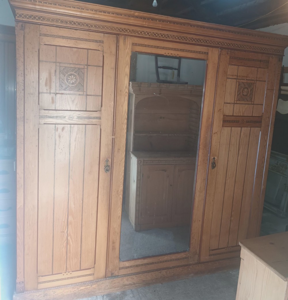 A large Victorian triple-door ash wardrobe featuring geometric marquetry inlay panels, a central mirrored door, and a heavily moulded upper cornice. View XXIII