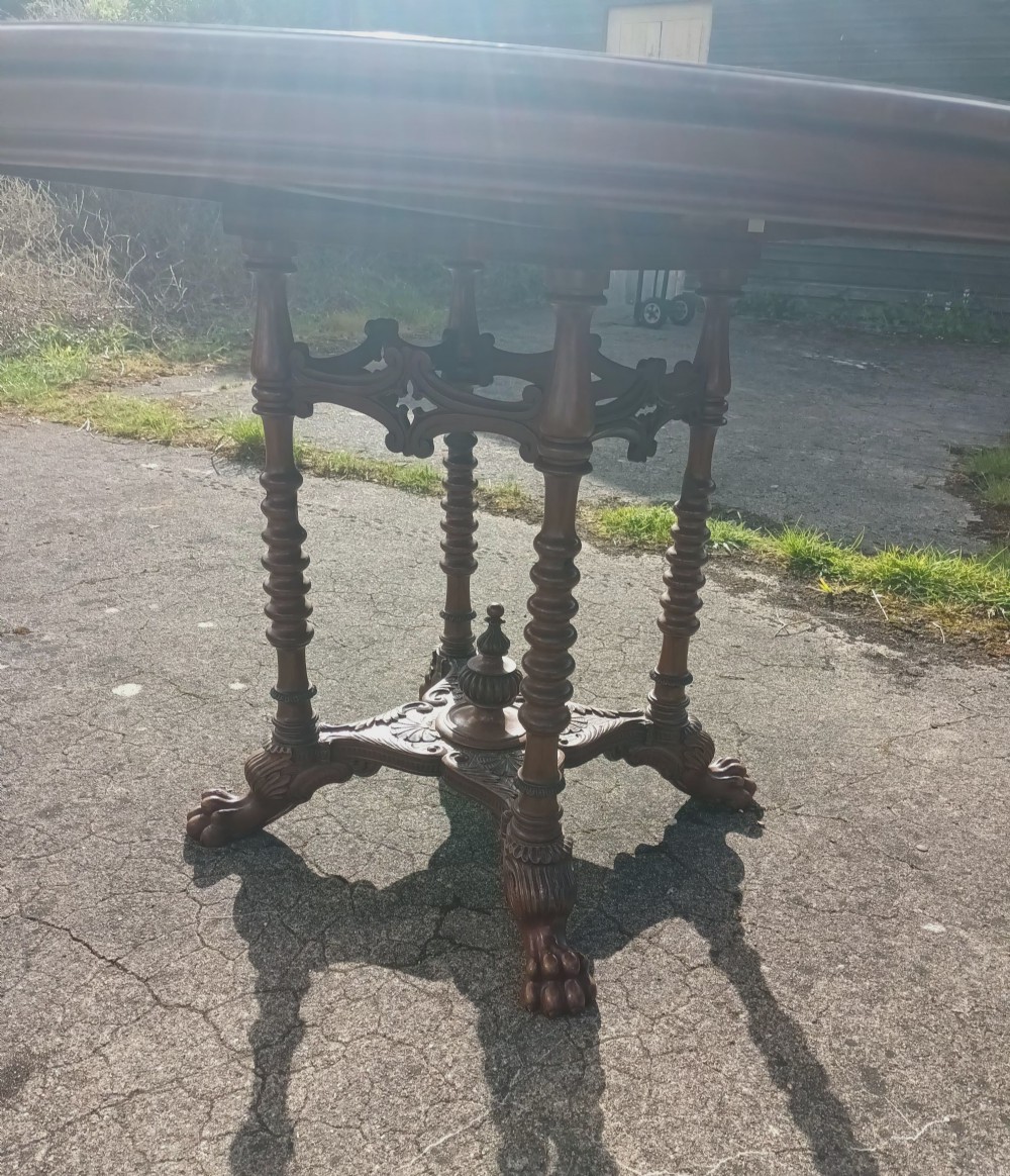 A late Victorian circular mahogany centre table featuring a polished top supported by turned columns and a carved base with carved feet. View VI
