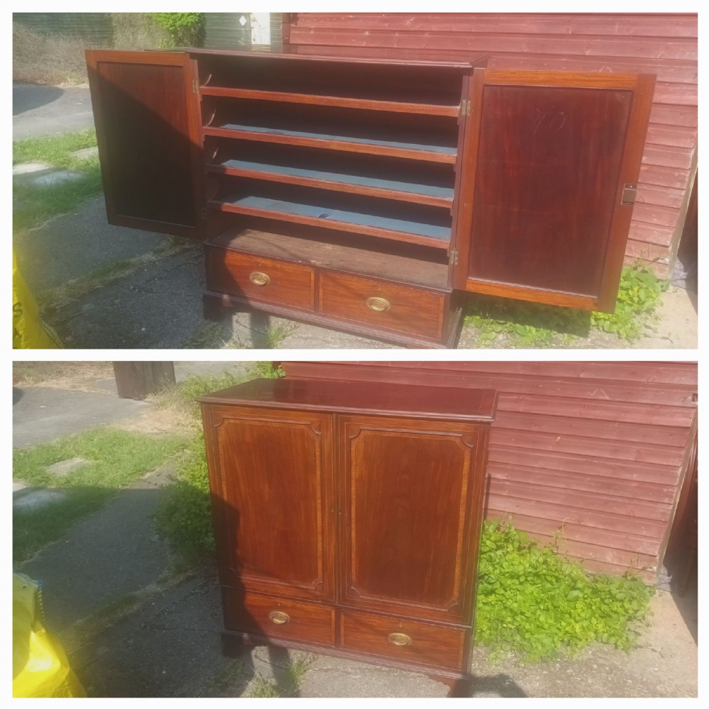 A warm brown mahogany dwarf linen press cupboard featuring two crossbanded cupboard doors above two lower drawers with brass handles. View II
