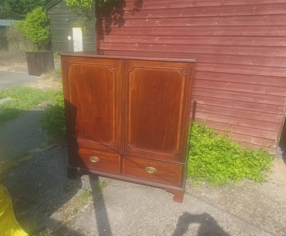 A warm brown mahogany dwarf linen press cupboard featuring two crossbanded cupboard doors above two lower drawers with brass handles. View VI