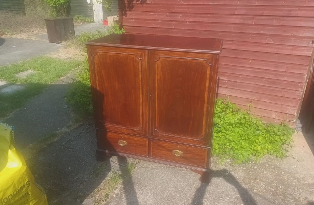 A warm brown mahogany dwarf linen press cupboard featuring two crossbanded cupboard doors above two lower drawers with brass handles. View VII