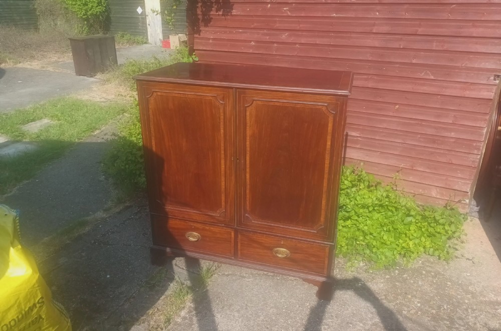 A warm brown mahogany dwarf linen press cupboard featuring two crossbanded cupboard doors above two lower drawers with brass handles. View VIII