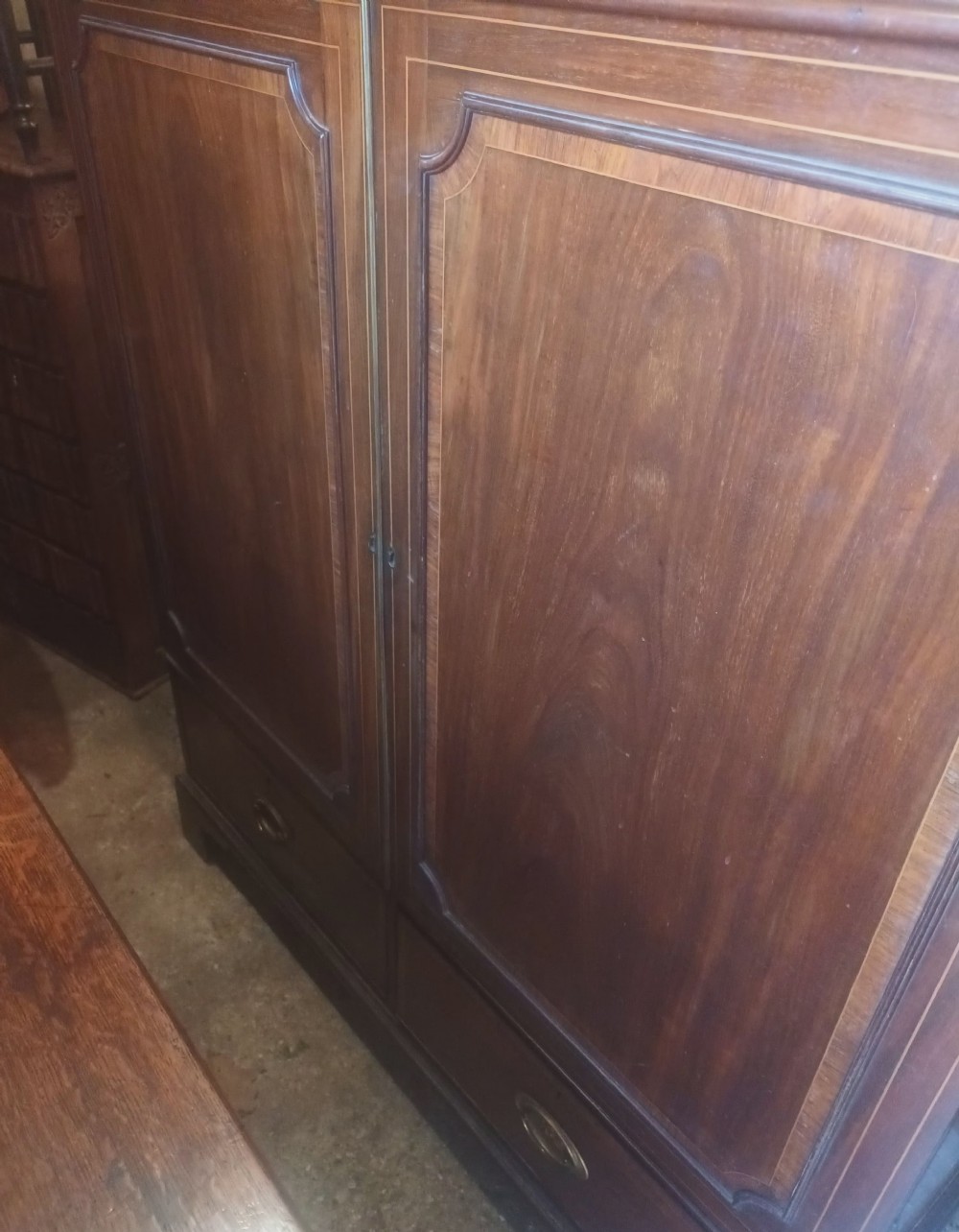 A warm brown mahogany dwarf linen press cupboard featuring two crossbanded cupboard doors above two lower drawers with brass handles. View XIV