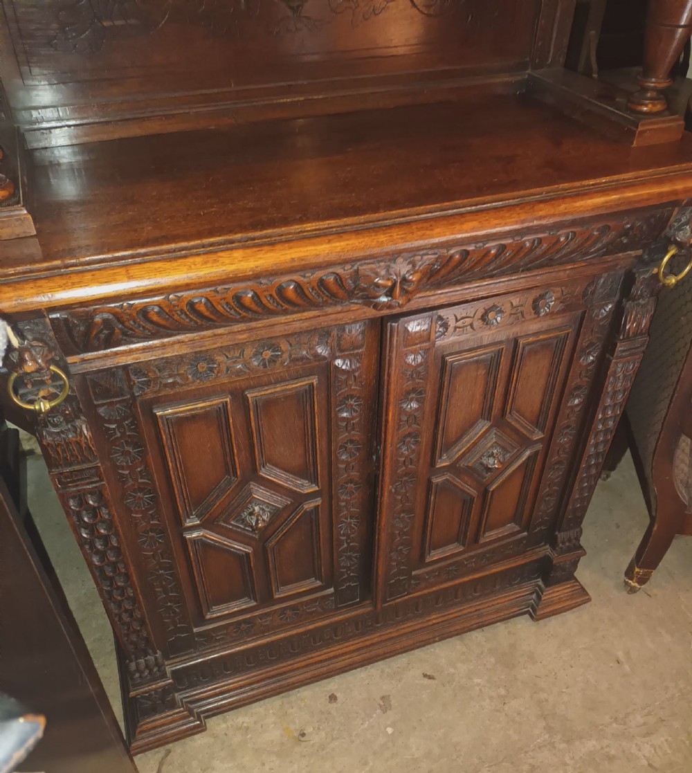 A dark Victorian carved oak bookcase with upper leaded glass doors, middle turned supports, and relief-carved lower panel doors. View IX