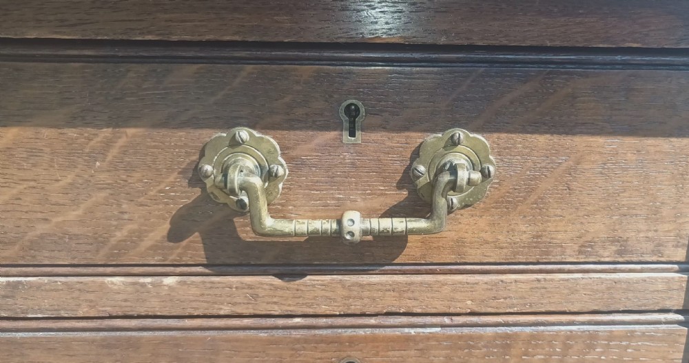 A late Victorian oak kneehole pedestal writing desk featuring nine drawers with brass handles and a green leather insert on the top surface. View V