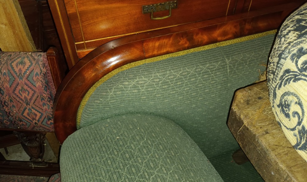A 19th-century mahogany hall sofa featuring carved floral scroll armrests, a mahogany wooden border, and green textured upholstery. View XV