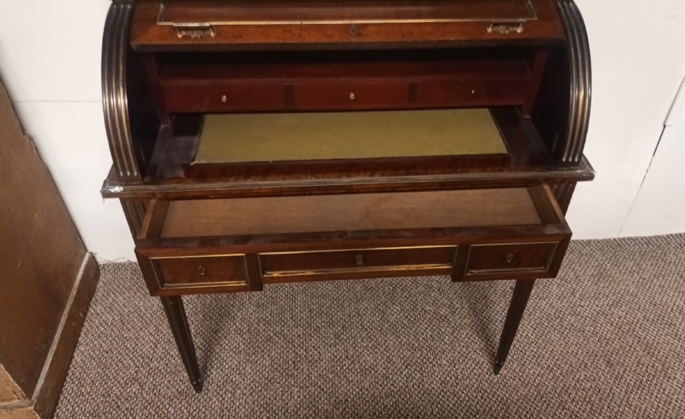 An antique French mahogany cylinder bureau featuring brass mouldings, a top pierced brass gallery, frieze drawers, and fluted legs. View IV