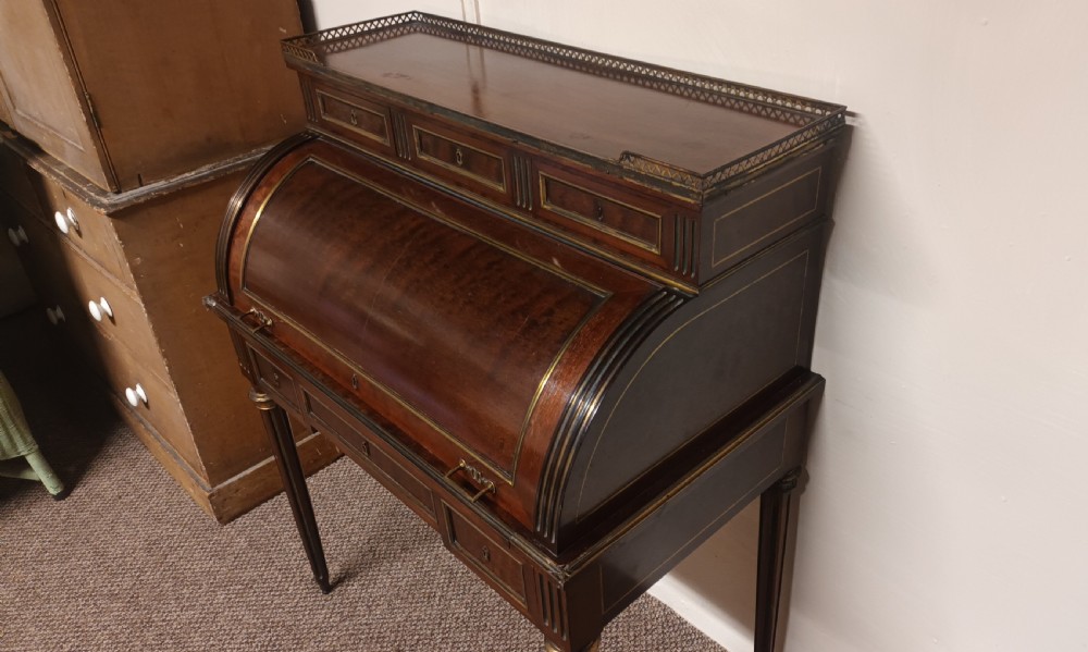 An antique French mahogany cylinder bureau featuring brass mouldings, a top pierced brass gallery, frieze drawers, and fluted legs. View VII