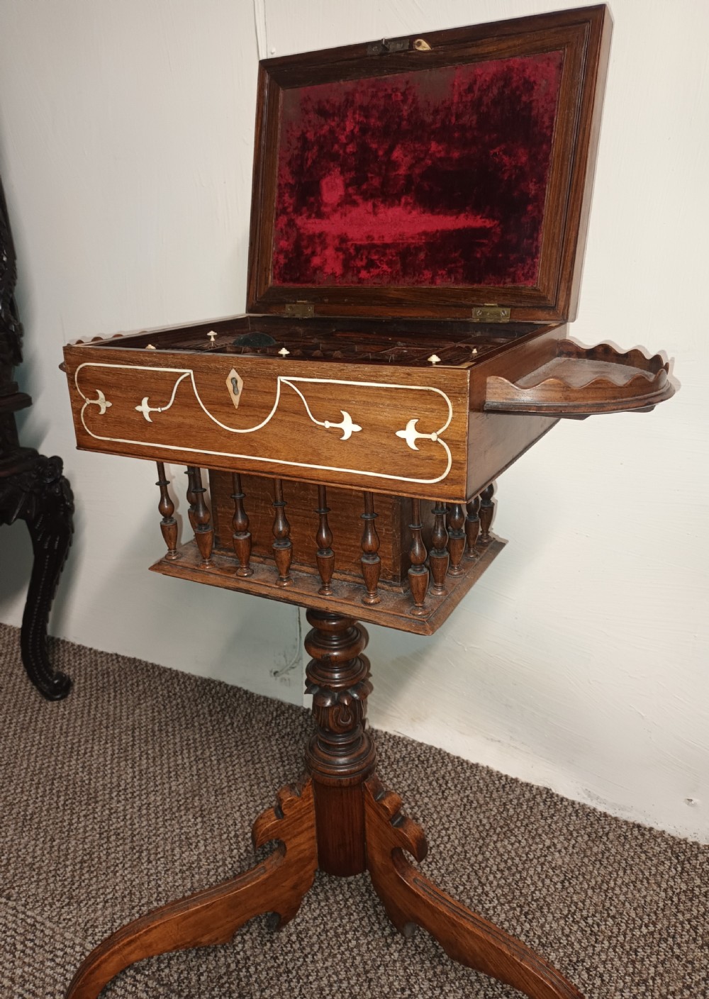 An Anglo-Indian rosewood work table featuring a hinged lid with velvet lining, fitted internal compartments, bone inlay, drop-leaf flaps, a spindle gallery, and a tripod pedestal base. View VIII