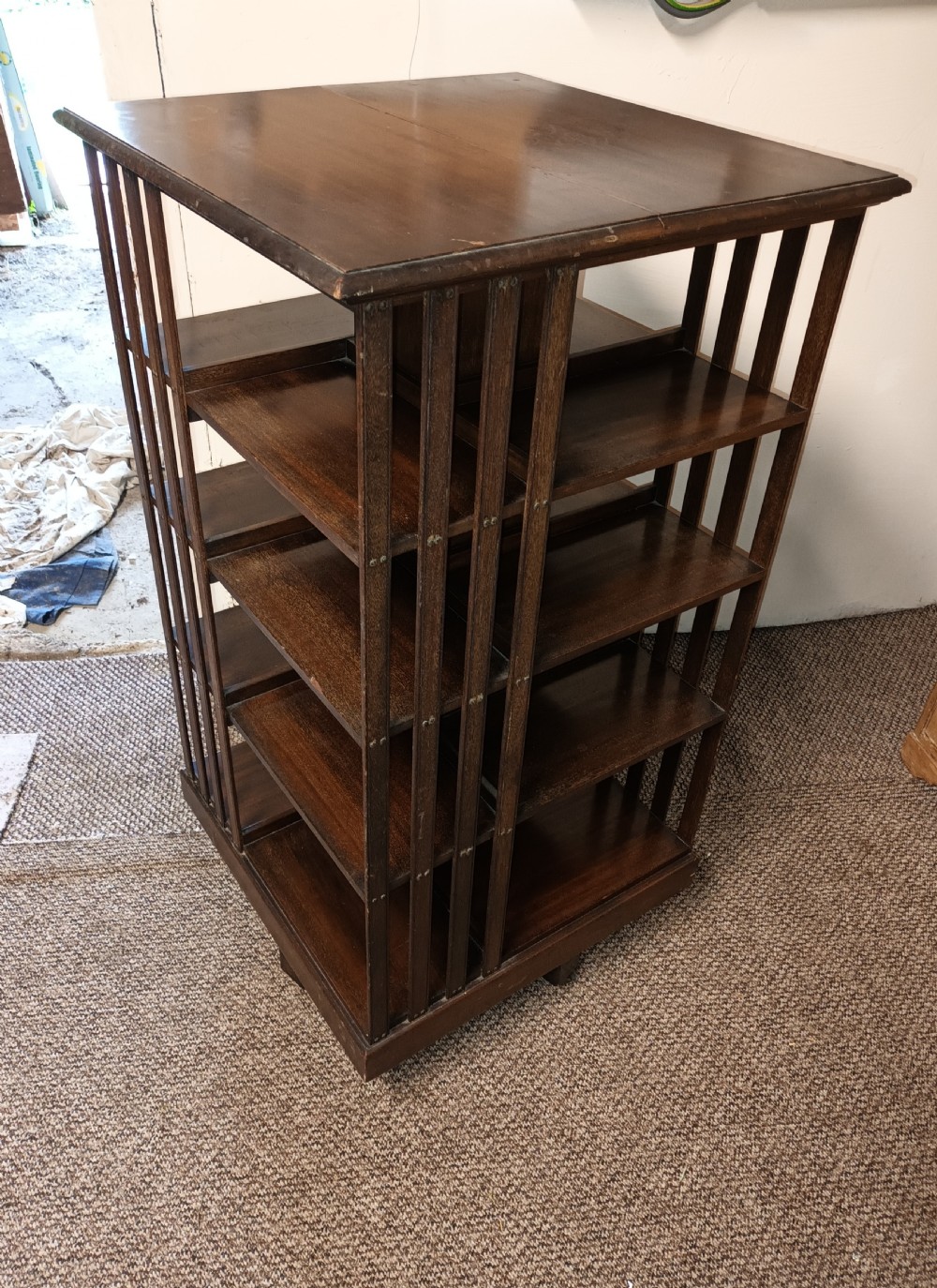 A square dark mahogany revolving bookcase featuring multi-tiered shelves and vertical side slats. View V