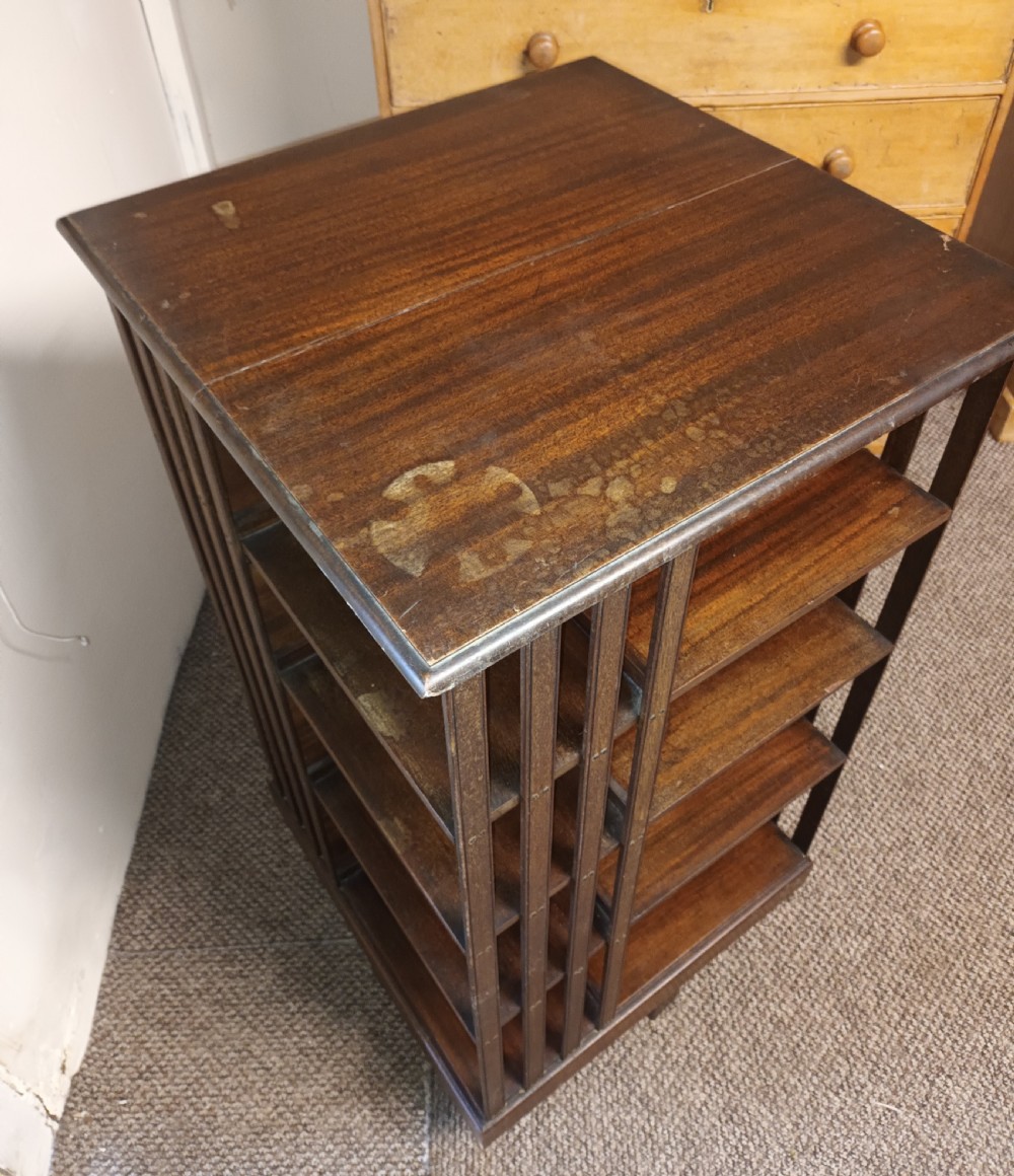 A square dark mahogany revolving bookcase featuring multi-tiered shelves and vertical side slats. View VIII
