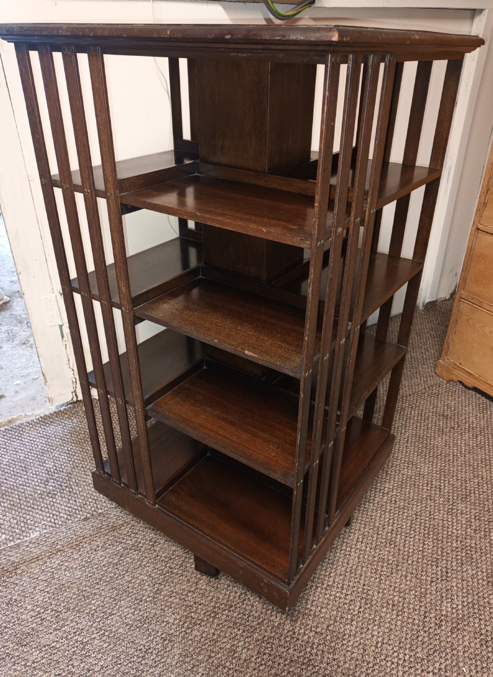 A square dark mahogany revolving bookcase featuring multi-tiered shelves and vertical side slats. View IX