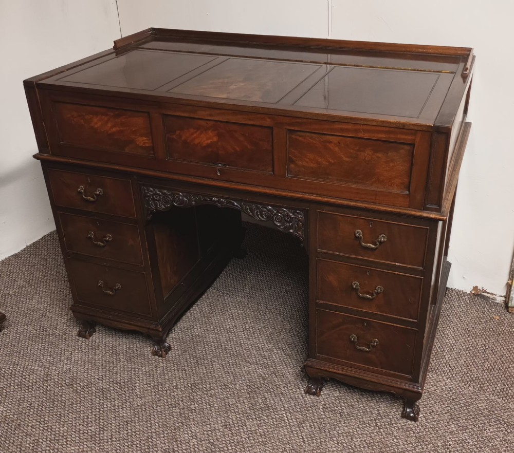 An Edwardian dark mahogany kneehole writing desk featuring a fitted upper superstructure, leather writing surface, twin drawer pedestals, brass handles, and claw feet. View V