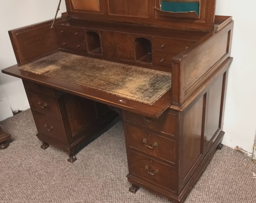 An Edwardian dark mahogany kneehole writing desk featuring a fitted upper superstructure, leather writing surface, twin drawer pedestals, brass handles, and claw feet. View XI