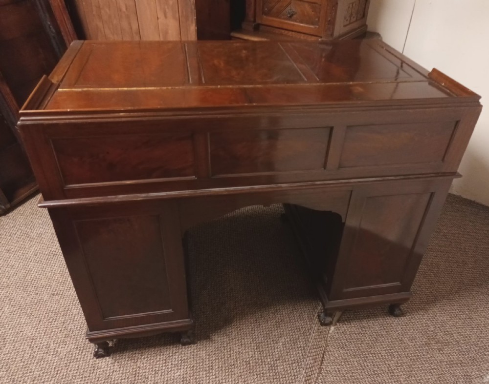 An Edwardian dark mahogany kneehole writing desk featuring a fitted upper superstructure, leather writing surface, twin drawer pedestals, brass handles, and claw feet. View XVI