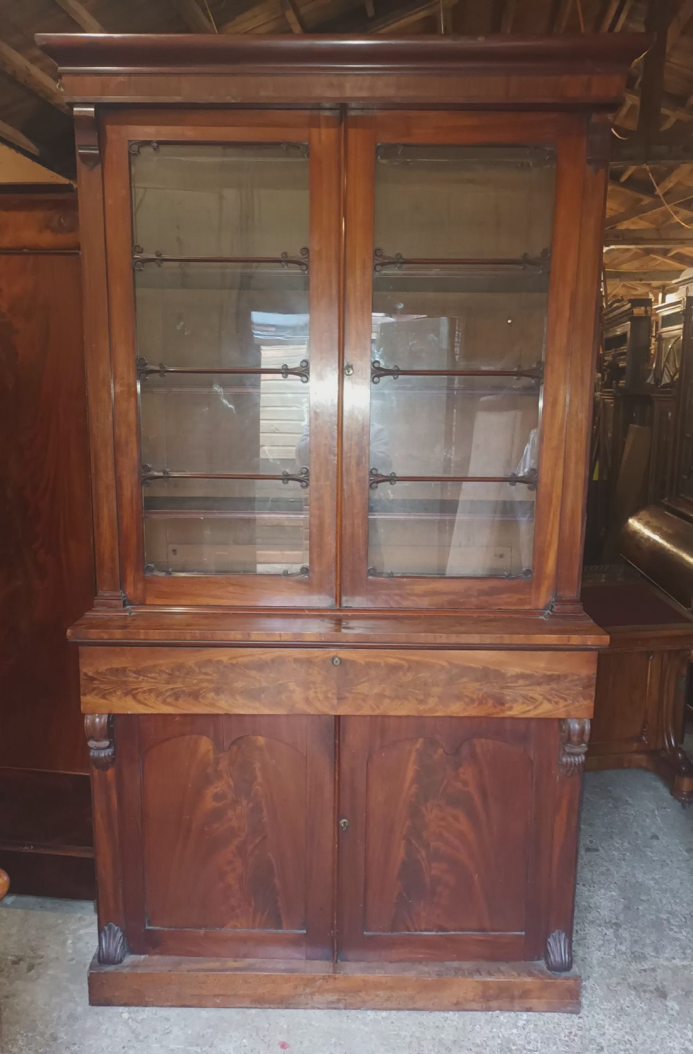 A tall 19th-century mahogany library bookcase featuring two upper glazed doors over a two-door cupboard base with flame mahogany veneer panels. View V