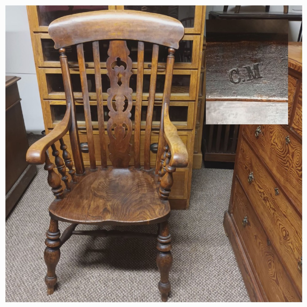 A dark-stained Victorian Windsor armchair with a spindled high back, carved central splat, shaped armrests, solid seat, and turned wooden legs. View X