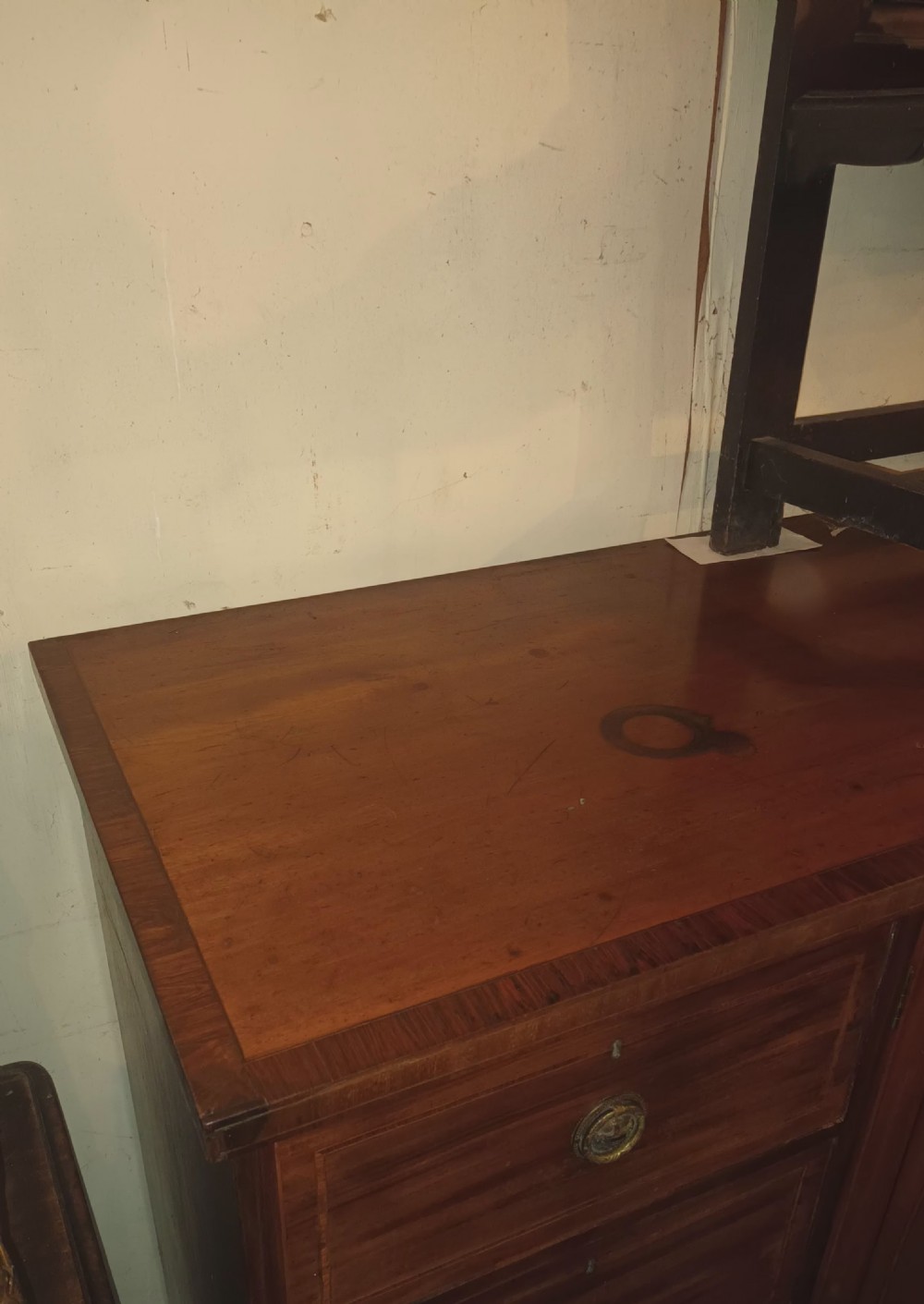 An antique warm brown mahogany dwarf linen press with central inlaid double doors flanked by two stacks of drawers and brass pull handles. View XXIV