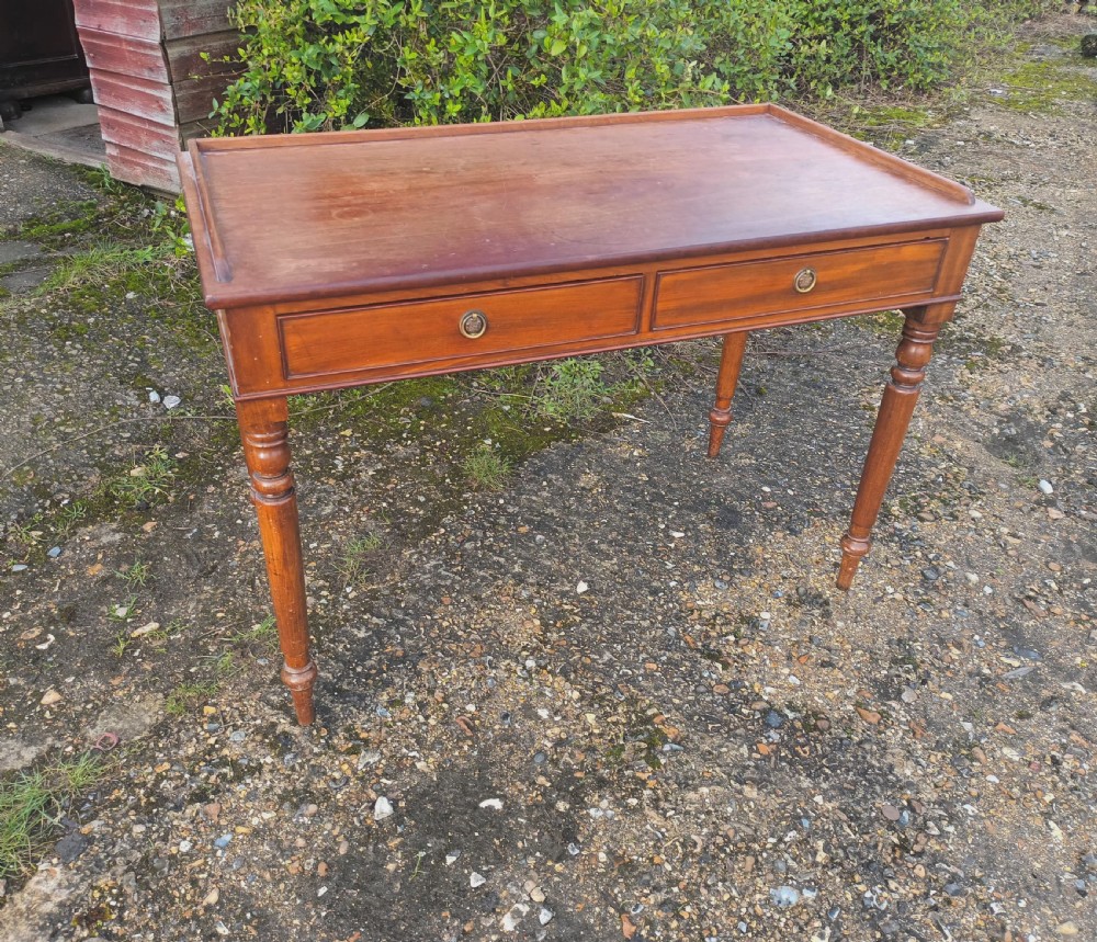 A Victorian mahogany writing table with a raised gallery edge, two front frieze drawers with brass ring handles, and four turned legs. View II