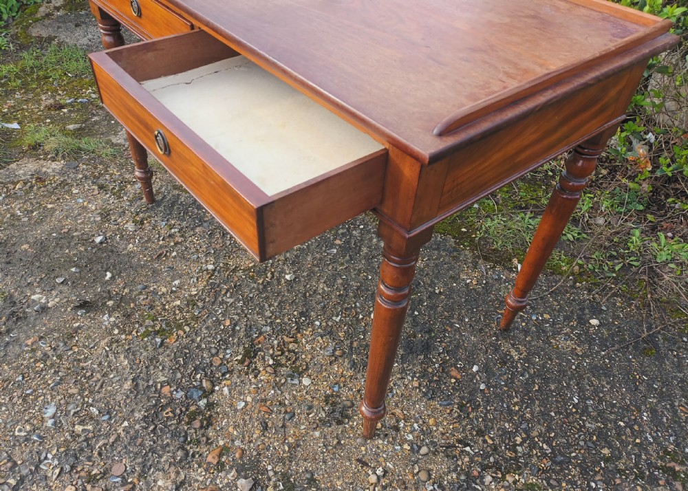 A Victorian mahogany writing table with a raised gallery edge, two front frieze drawers with brass ring handles, and four turned legs. View III
