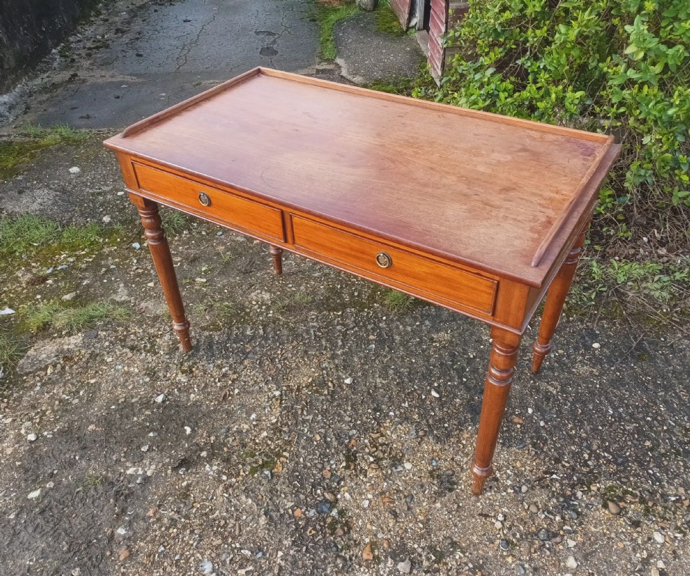 A Victorian mahogany writing table with a raised gallery edge, two front frieze drawers with brass ring handles, and four turned legs. View V