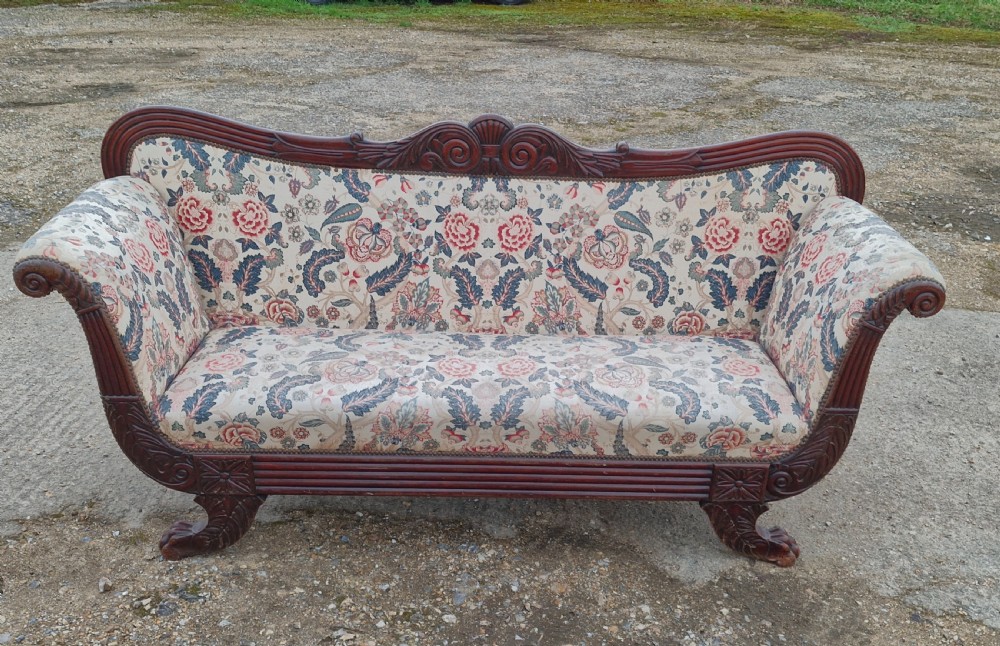 An early Victorian carved mahogany sofa with scroll arms and cream floral patterned upholstery. View II
