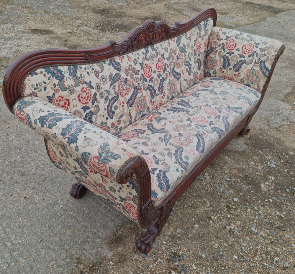 An early Victorian carved mahogany sofa with scroll arms and cream floral patterned upholstery. View V