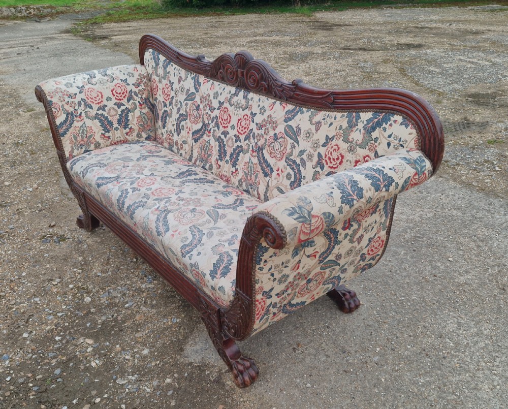 An early Victorian carved mahogany sofa with scroll arms and cream floral patterned upholstery. View VI