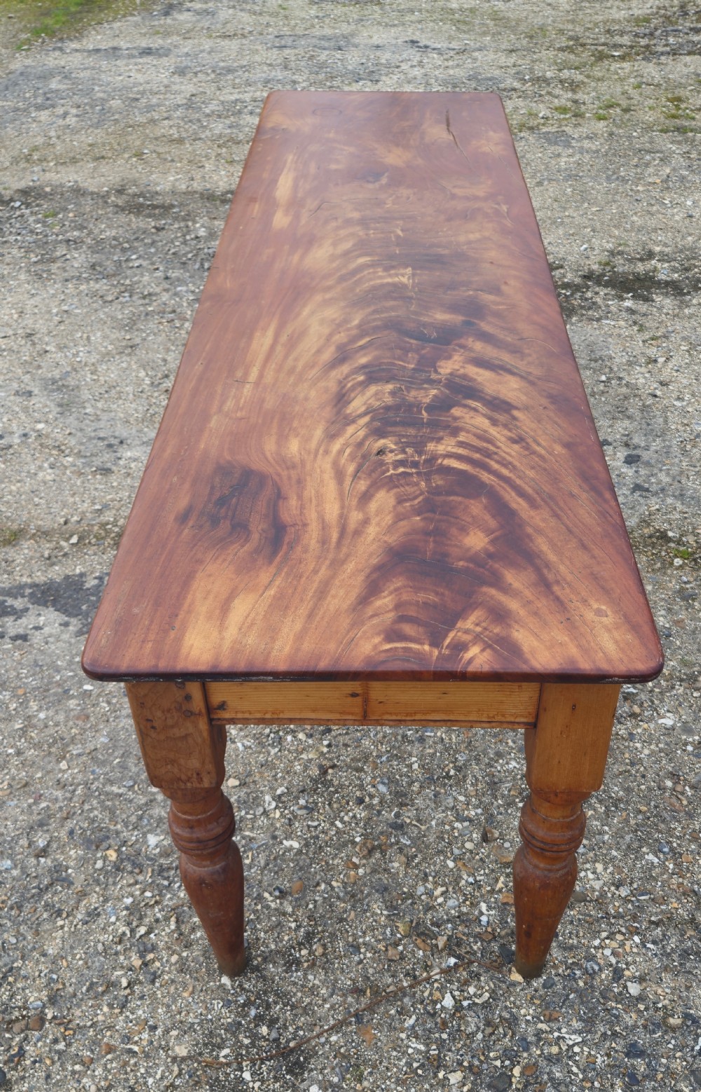A long Victorian pine kitchen dining table featuring a single-board top with visible wood grain and four turned legs. View VI