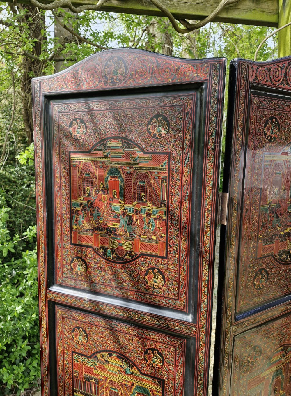 A five-panel Burmese folding screen decorated with red and black lacquered panels depicting detailed architectural scenes. View IV