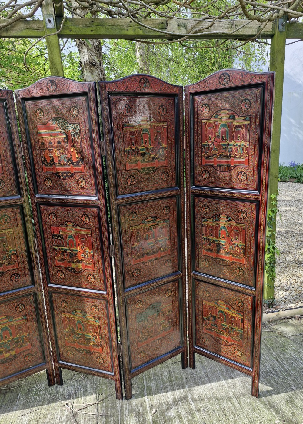 A five-panel Burmese folding screen decorated with red and black lacquered panels depicting detailed architectural scenes. View V