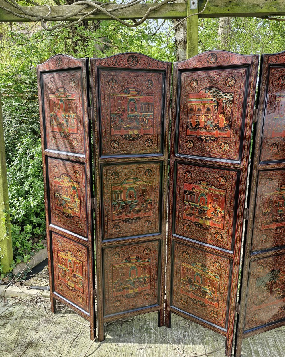 A five-panel Burmese folding screen decorated with red and black lacquered panels depicting detailed architectural scenes. View VI