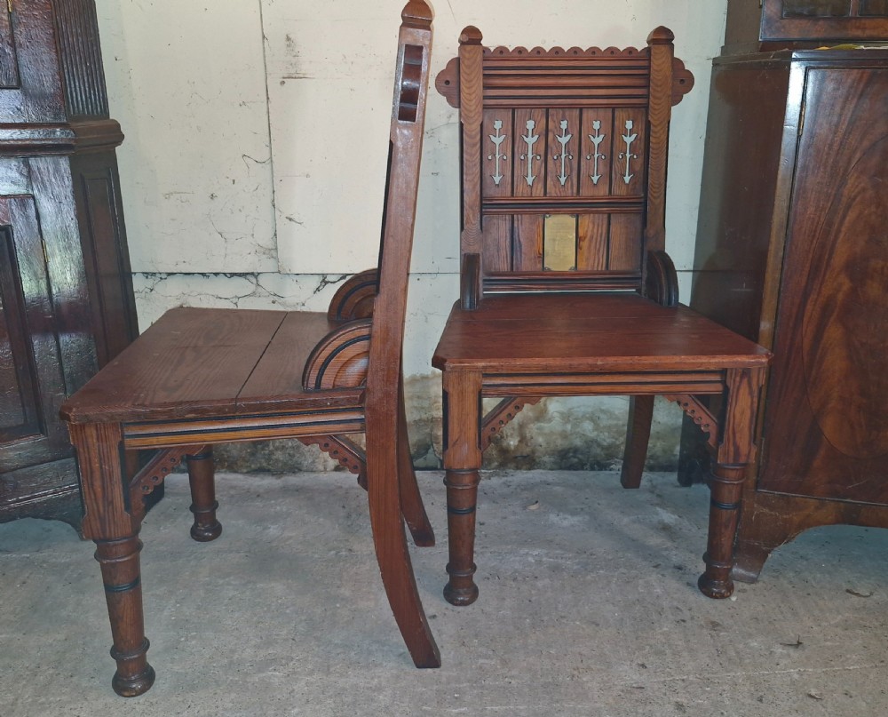 A pair of Victorian pitch pine hall chairs featuring pierced Gothic carved backs, solid wooden seats, and turned front legs. View VIII