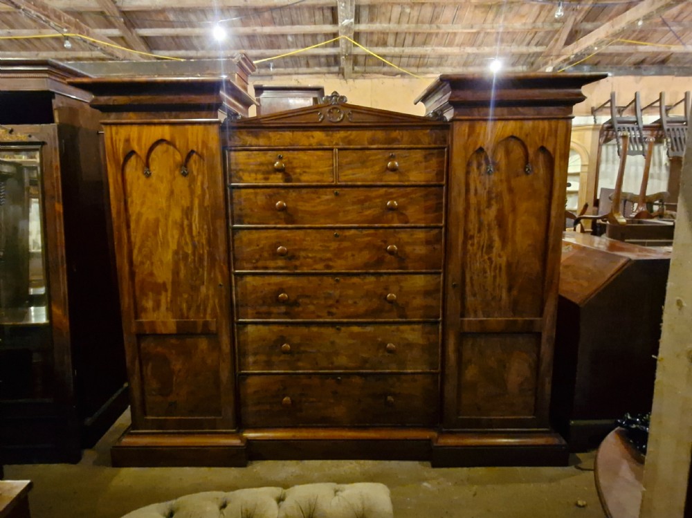 A large early Victorian mahogany sentry box combination wardrobe featuring twin outer cupboards with gothic arch panels flanking a central bank of drawers. View VII