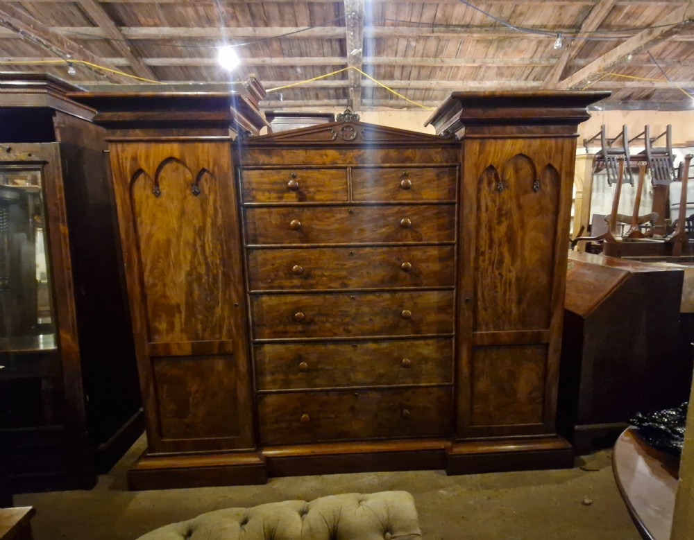 A large early Victorian mahogany sentry box combination wardrobe featuring twin outer cupboards with gothic arch panels flanking a central bank of drawers. View VIII