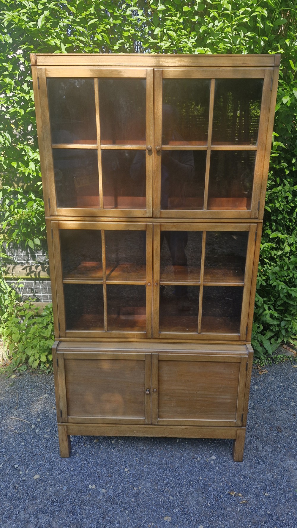 A three-tier mahogany sectional bookcase with two upper glazed double doors and a solid wooden cupboard base.